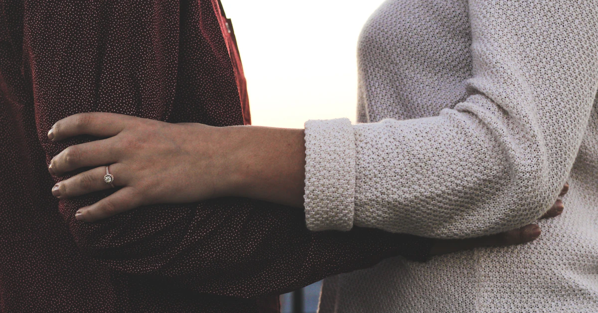 person in gray sweater holding black and red textile
