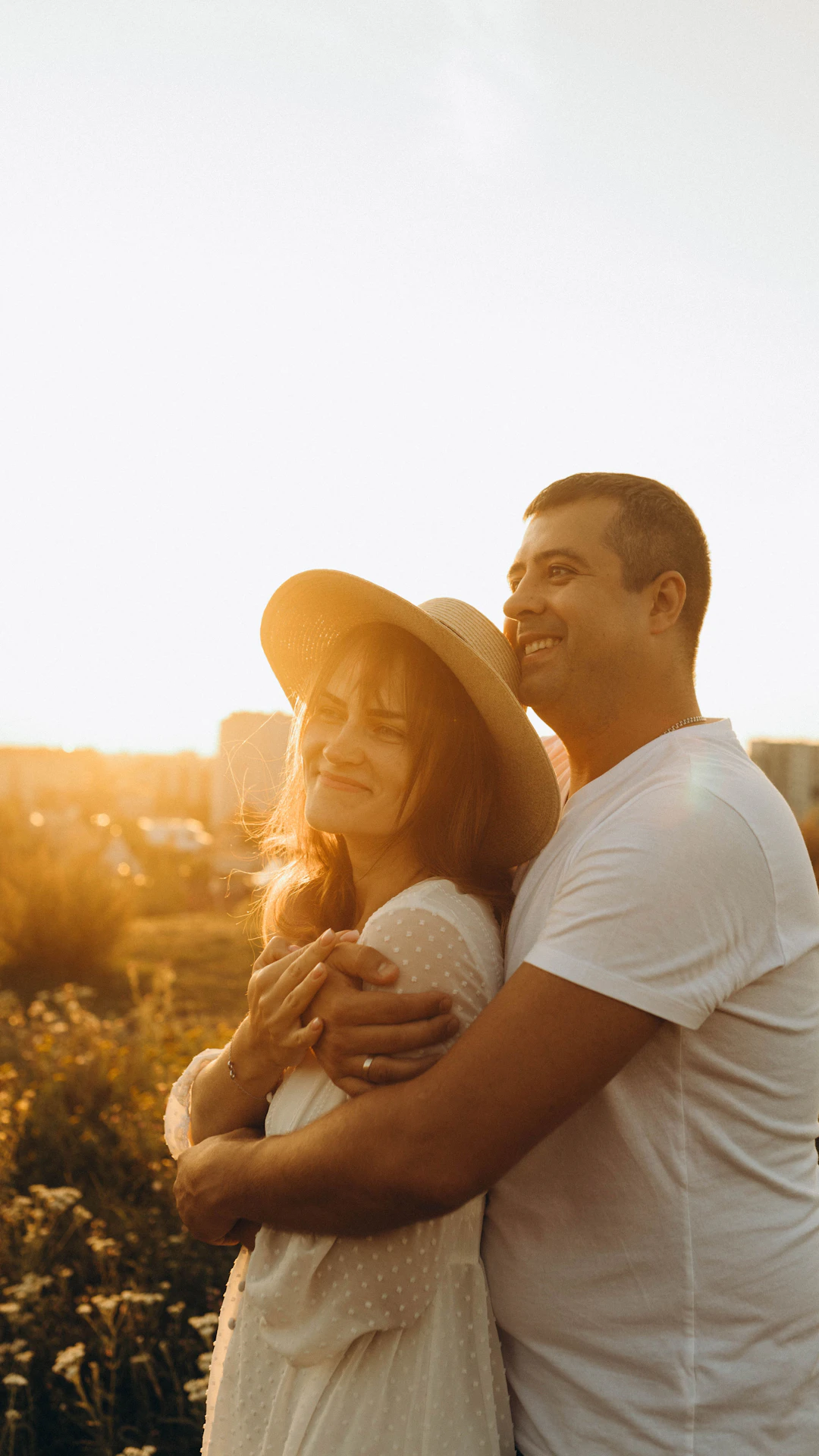 A man and a woman standing in a field at sunset
