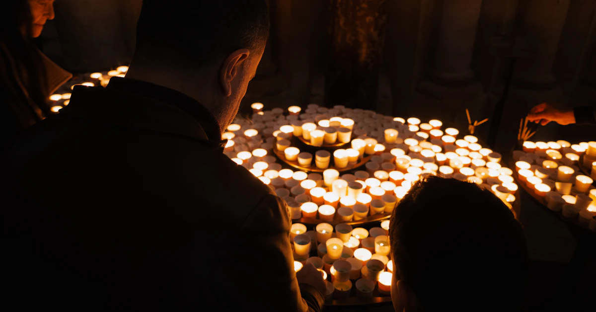 People gathered around many lit candles in darkness