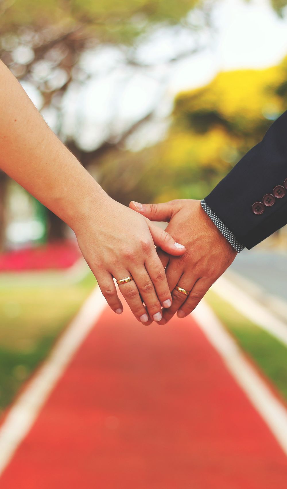 Close-up of a couple's hands with wedding rings, symbolizing love and togetherness outdoors.