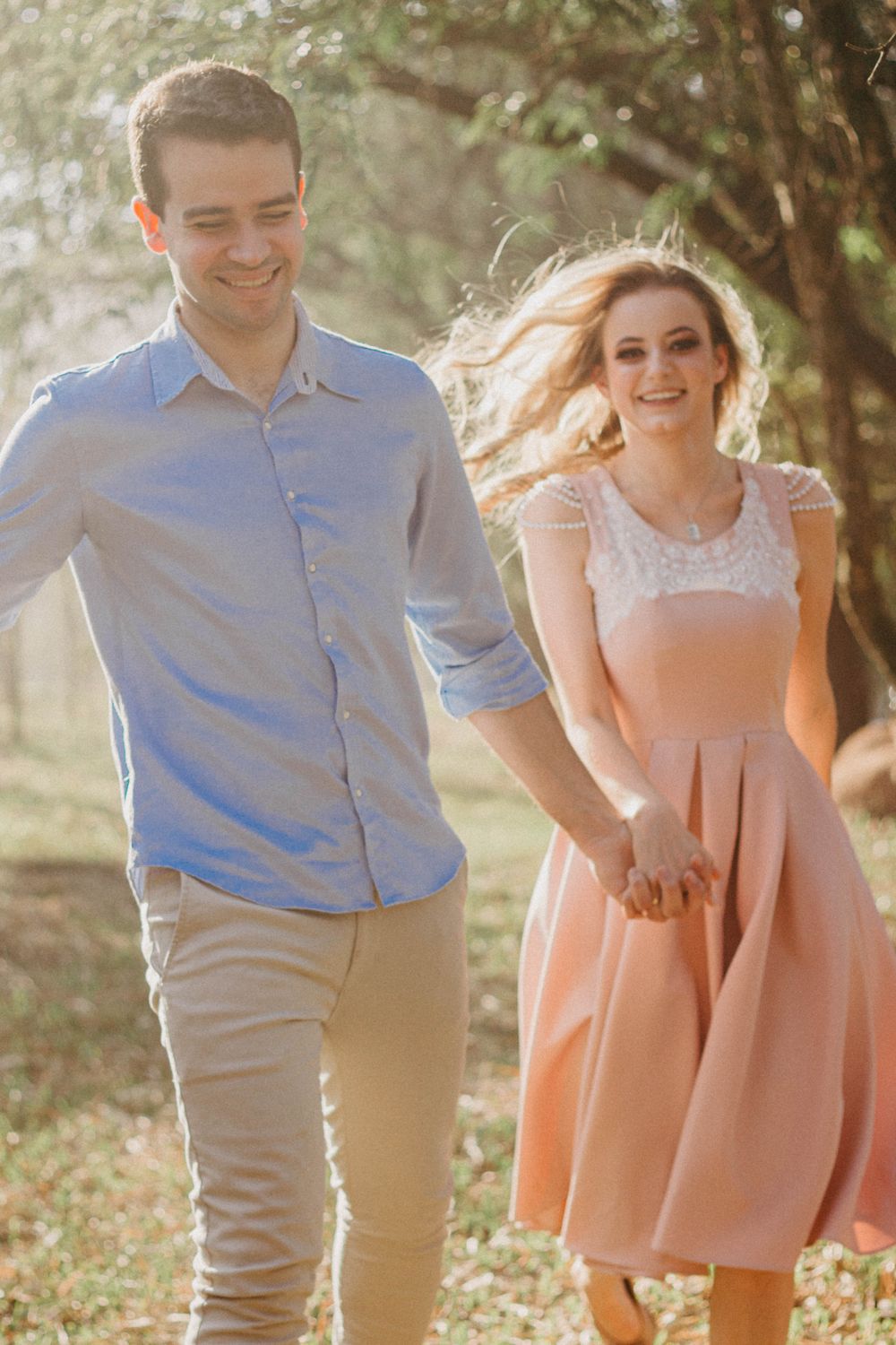 A happy couple holding hands and running through a sunny park, enjoying a carefree day together.