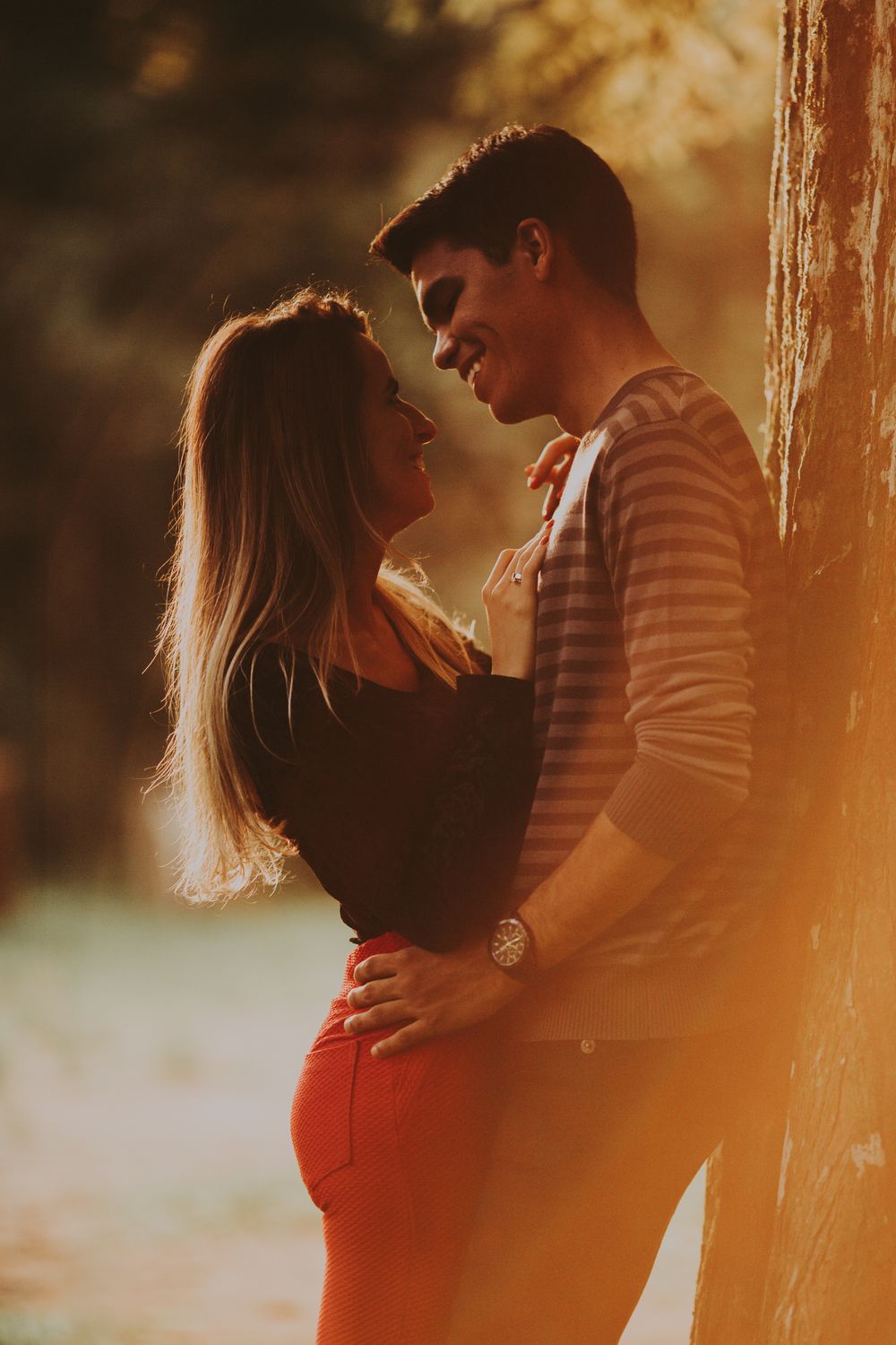 A couple shares a tender moment by a tree during a beautiful sunset.