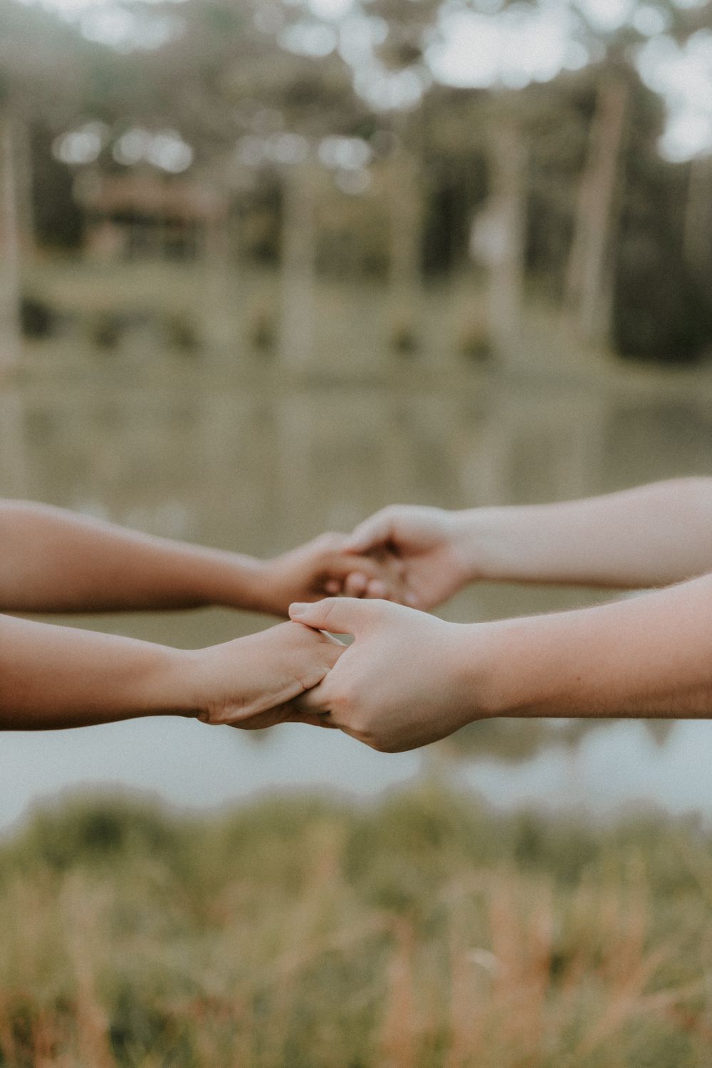 A couple holding hands near a lake, symbolizing love and connection in a tranquil outdoor setting.
