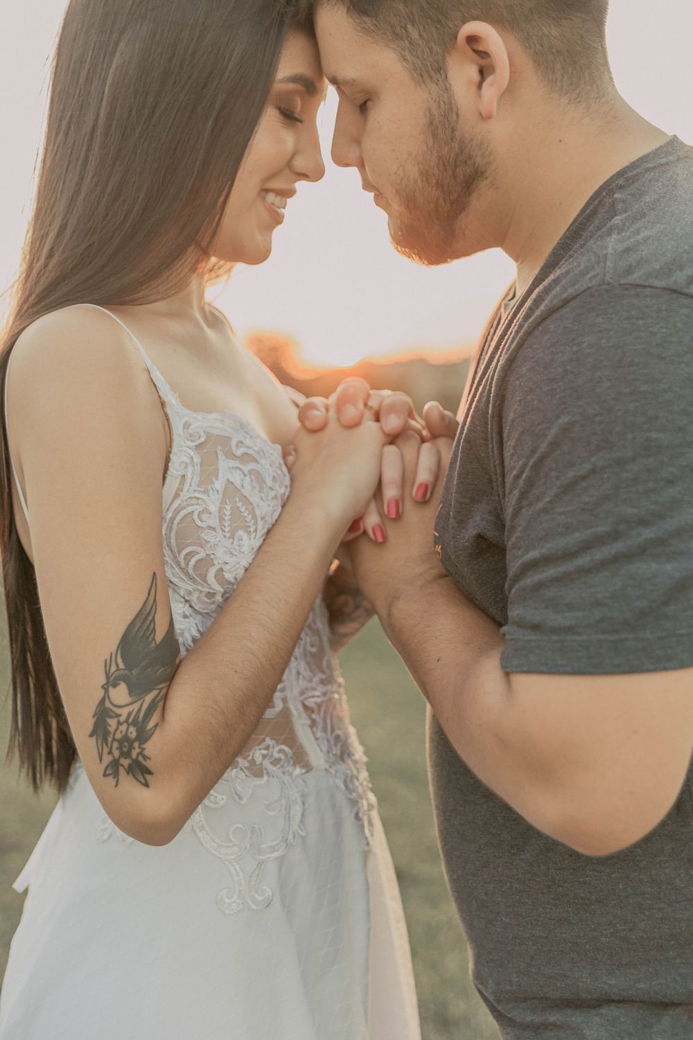 A tender moment of a couple embracing with hands together during sunset outdoors.