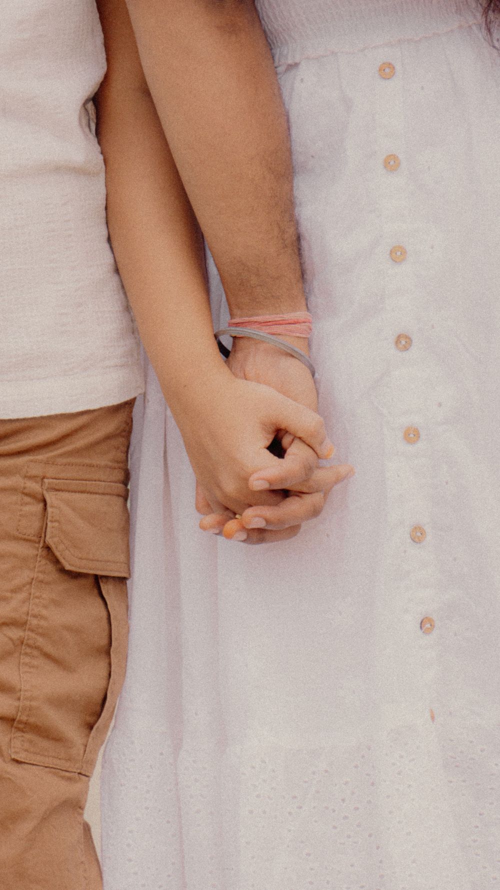 A close-up of a couple holding hands dressed in summer clothing, symbolizing love and connection.