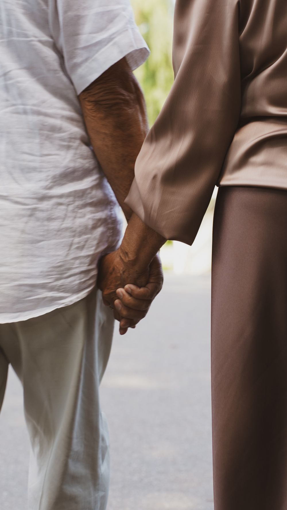 Elderly couple holding hands, symbolizing warmth and connection in an outdoor setting.