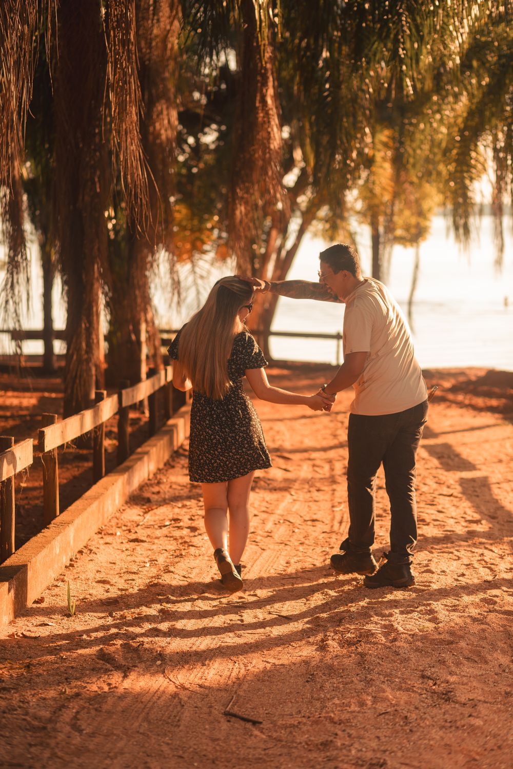 A joyful couple dances on a sunlit path, surrounded by nature, embodying romance and happiness.