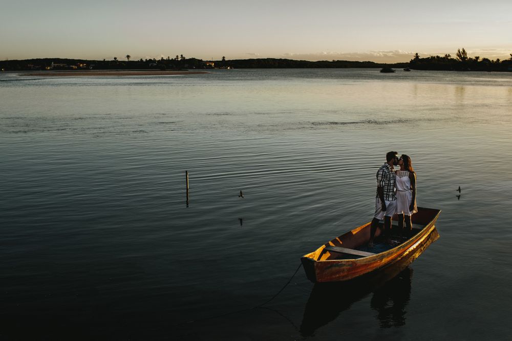 From above of young romantic couple kissing while standing in fishing boat floating on calm lake in evening