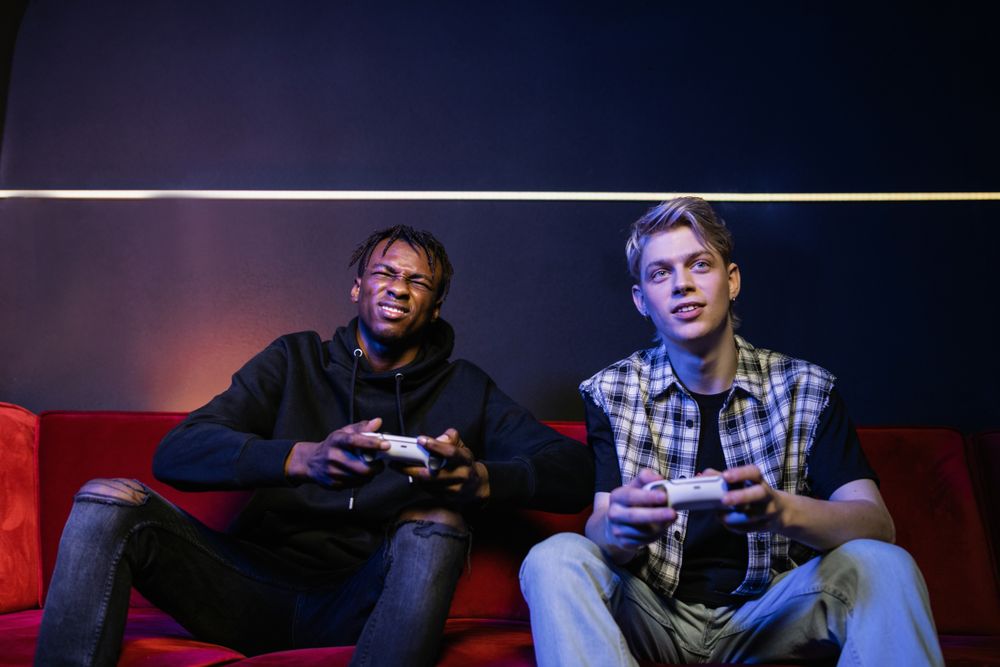 Two young men enjoying video games together on a couch, capturing leisure and friendship.
